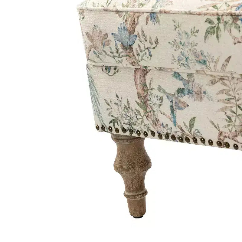 Fauteuil rembourré en bois avec motif floral, accoudoirs à panneaux et dossier en forme de bosse de chameau.