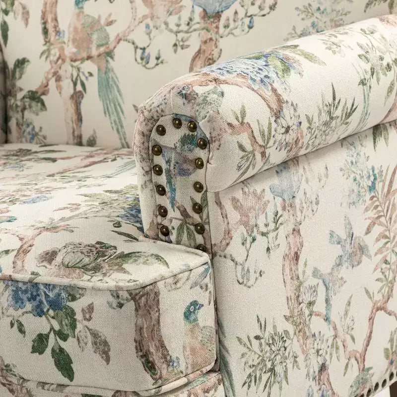 Fauteuil rembourré en bois avec motif floral, accoudoirs à panneaux et dossier en forme de bosse de chameau.